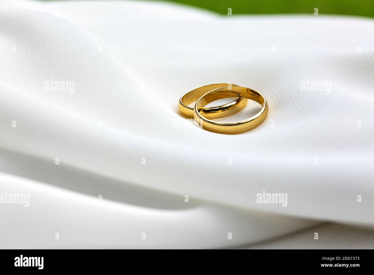 Couple of golden wedding rings laid on a white fabric, marriage reports Stock Photo