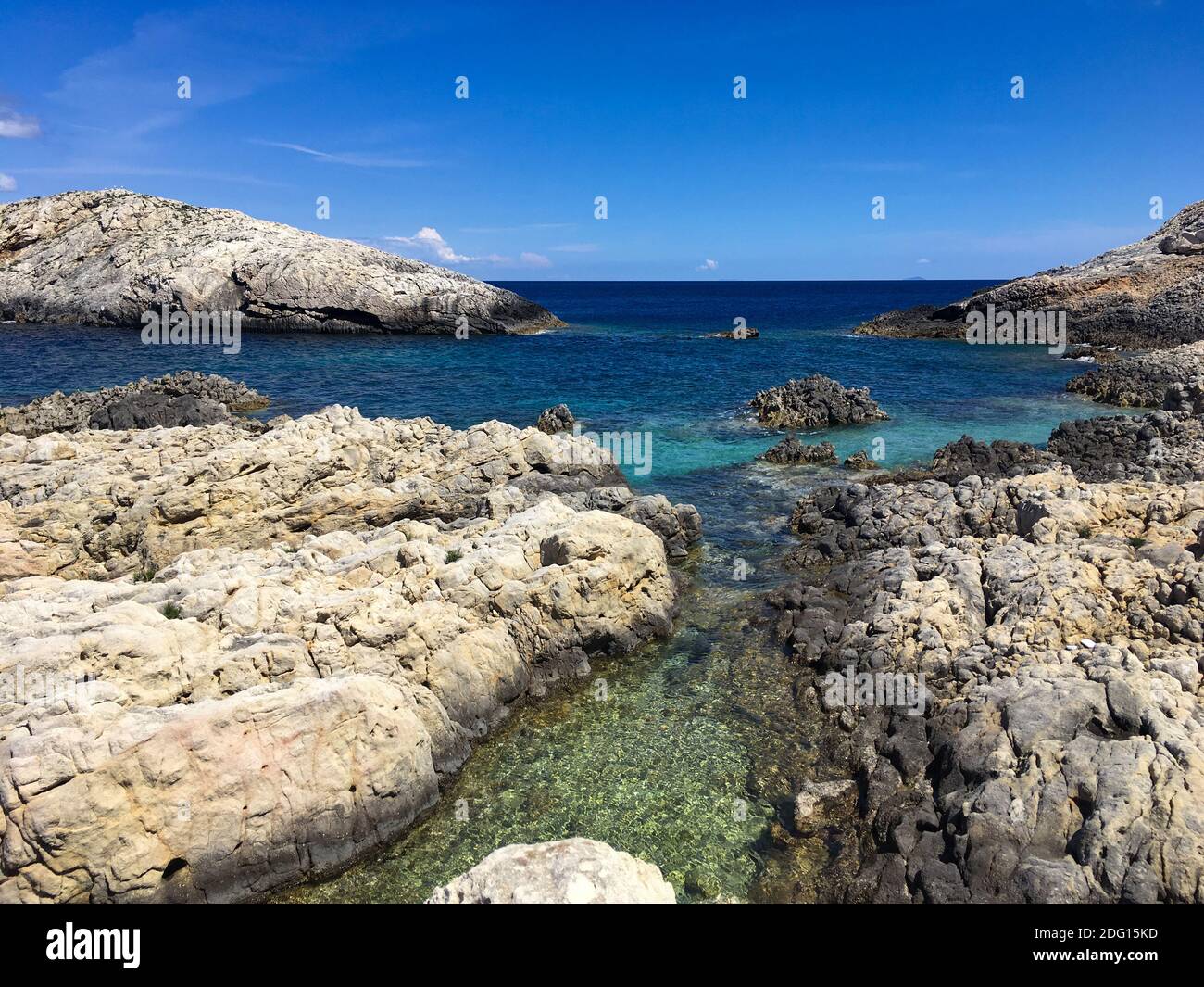 Rocky beach and crystal clear blue water Stock Photo - Alamy