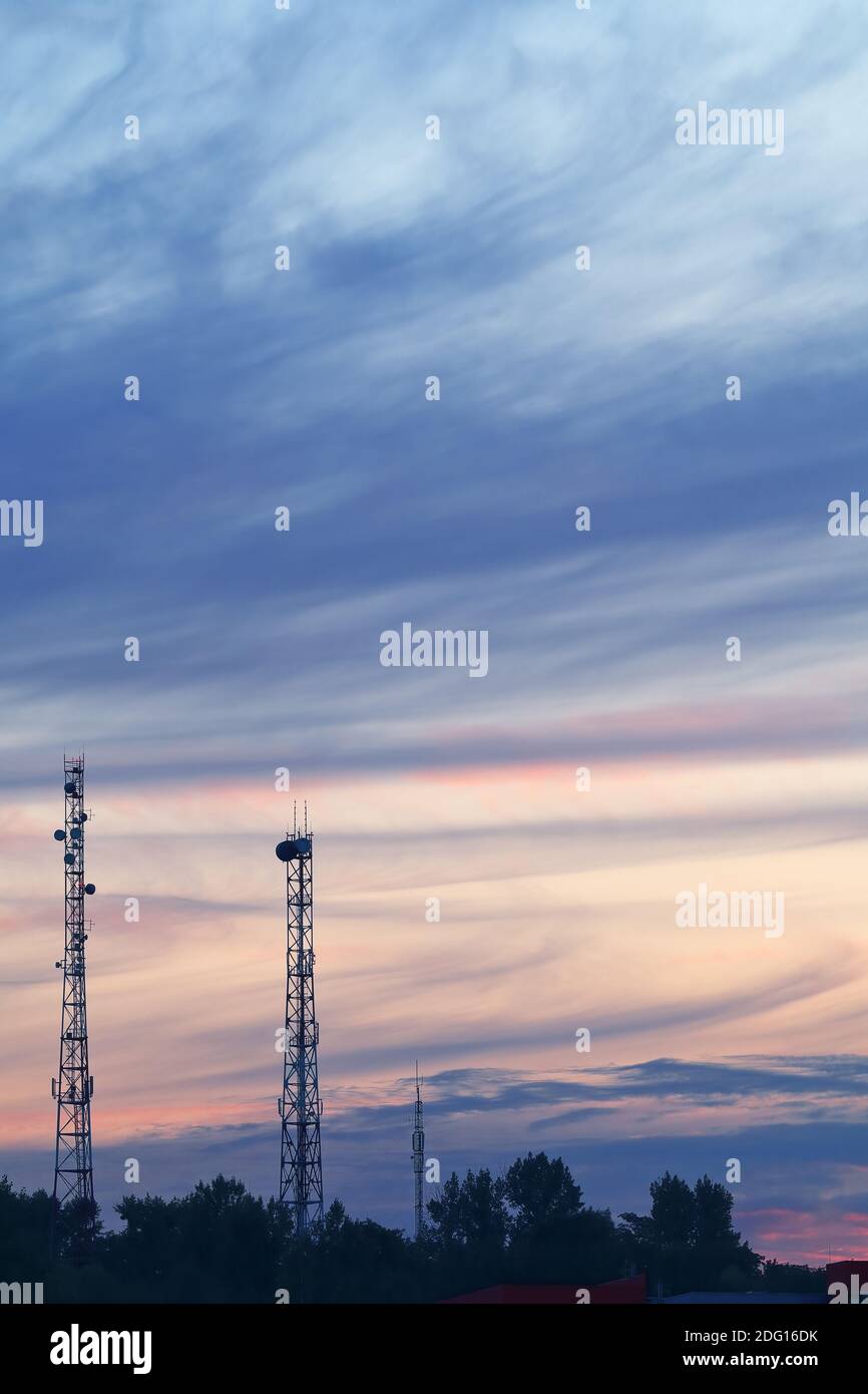Evening summer landscape with two high-rise telecommunication towers on background of cloudy sunset Stock Photo