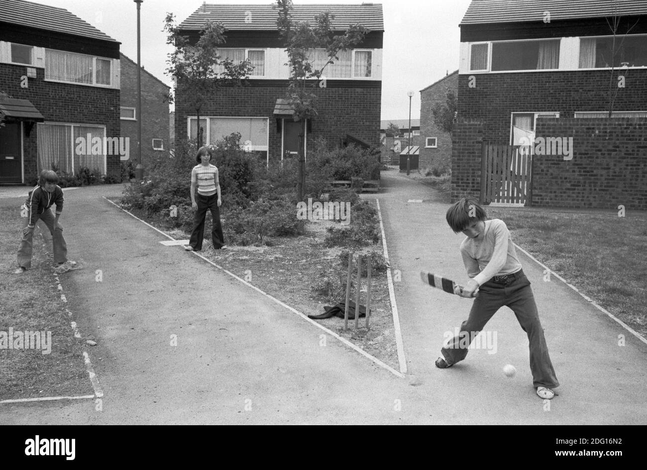 1970s England kids playing cricket outside in a traffic free pedestrian walkways. Boys and a girl  who live in this recently built modern housing estate. A new town development  1977 UK Milton Keynes, Buckinghamshire HOMER SYKES. Stock Photo