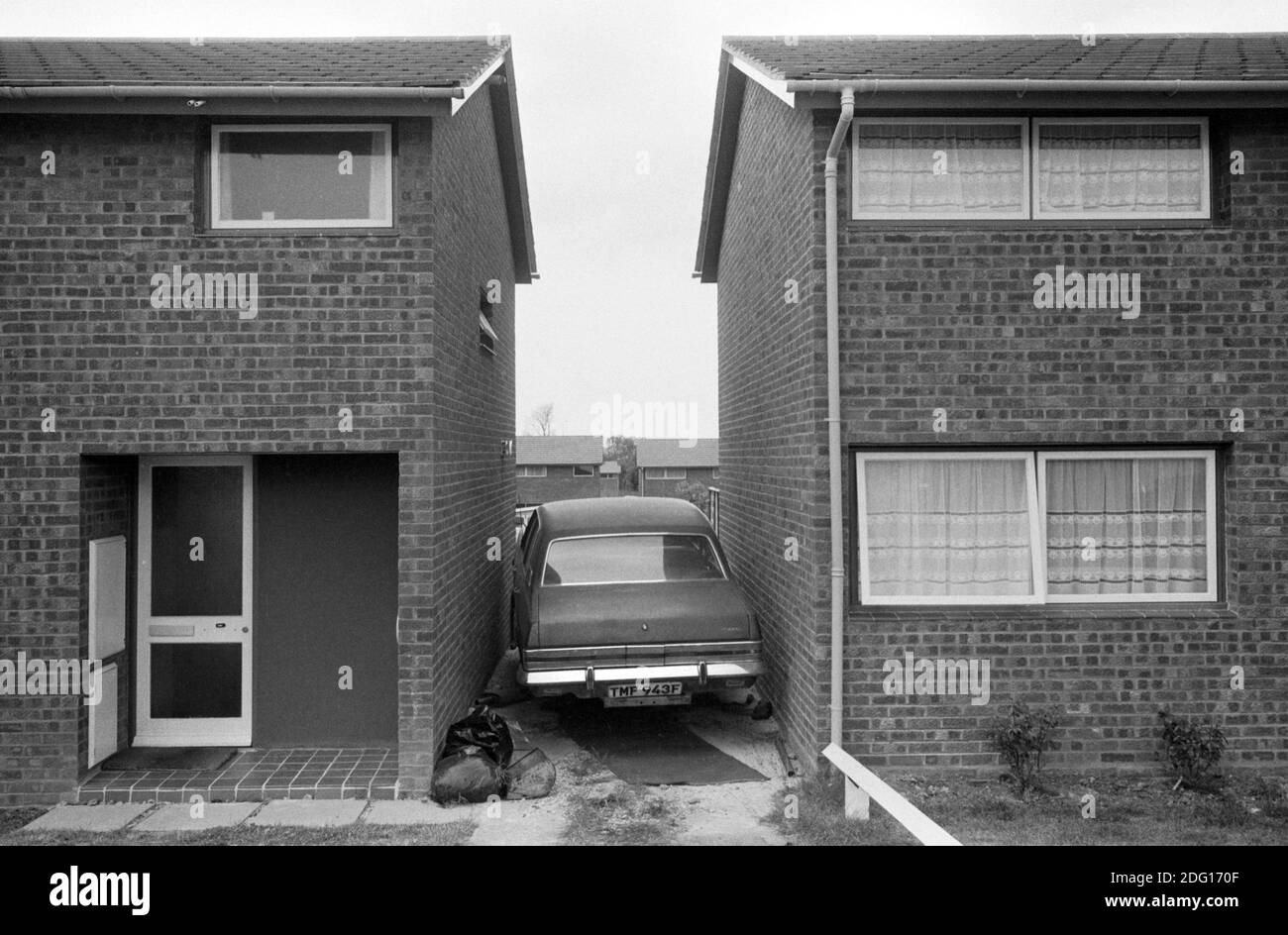 Modern housing estate 1970s England. End of terrace houses car stick between the two homes.  1977 HOMER SYKES Stock Photo