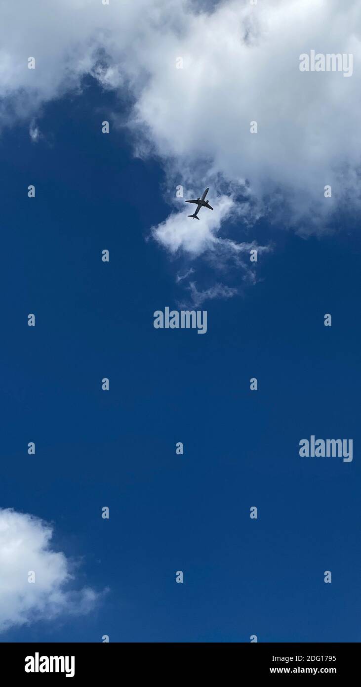 Airplane flying in the blue sky among clouds and sunlight Stock Photo ...