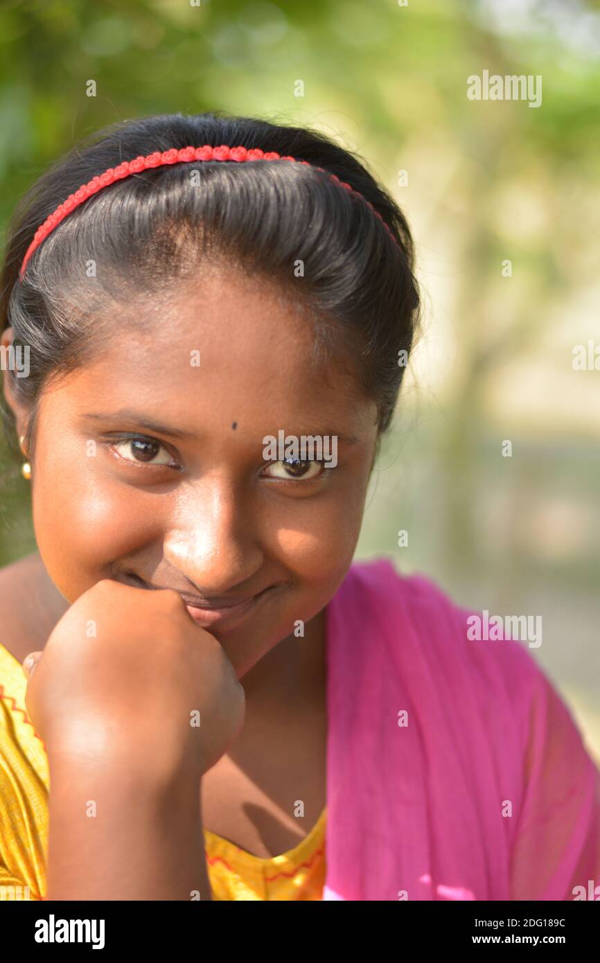 Close up of an Indian village teenage girl smiling with flower in hand and  wearing hair band and gold earring Stock Photo - Alamy
