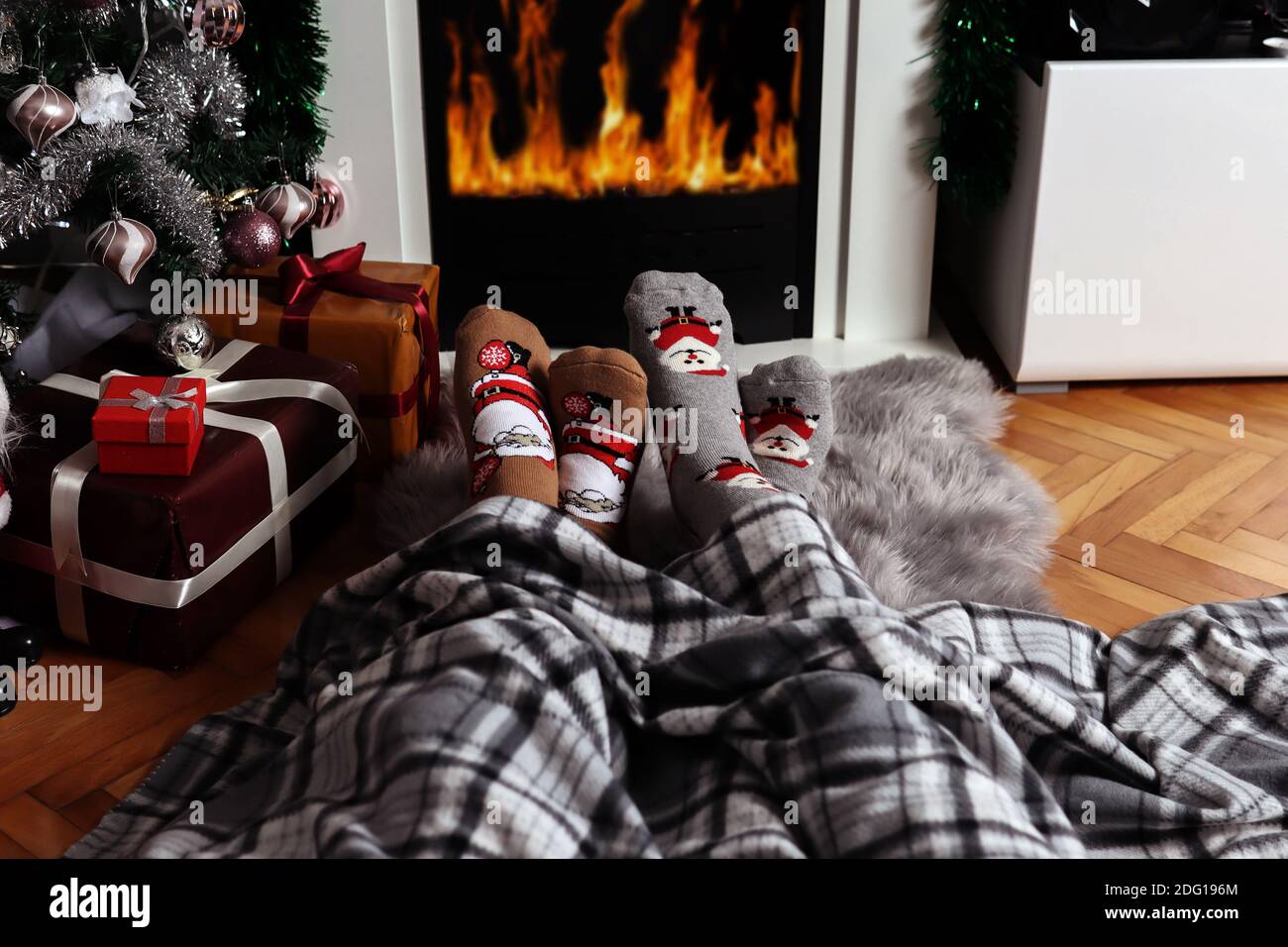 Couple in love sitting on the floor at home and warms feet on fireplace ...