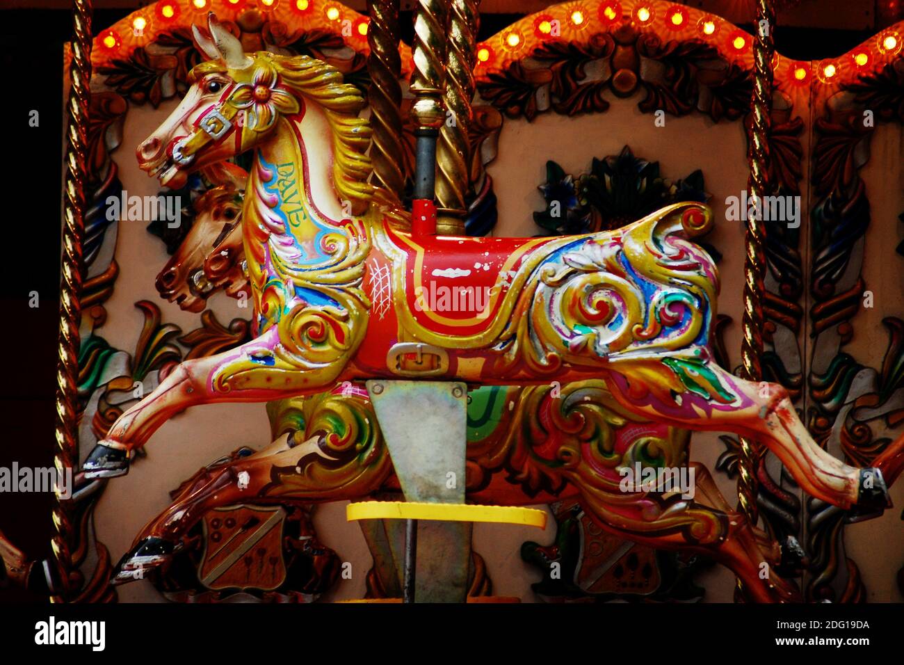 A horse called Dave is caught, mid cycle, on a British merry-go-round. Seaside or fairground children's attractions are AKA carousels  flying horses. Stock Photo