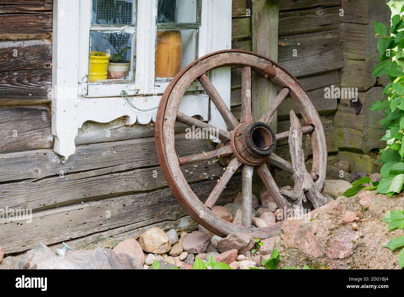 Old wooden wheel in willage near old wodden house in Lithuania Stock Photo