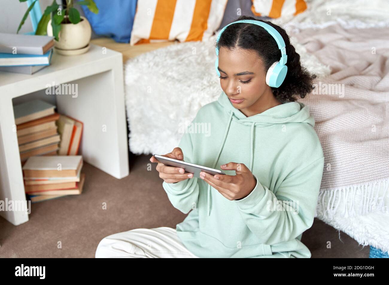Happy african teen girl watching videos on digital tablet at home. Stock Photo