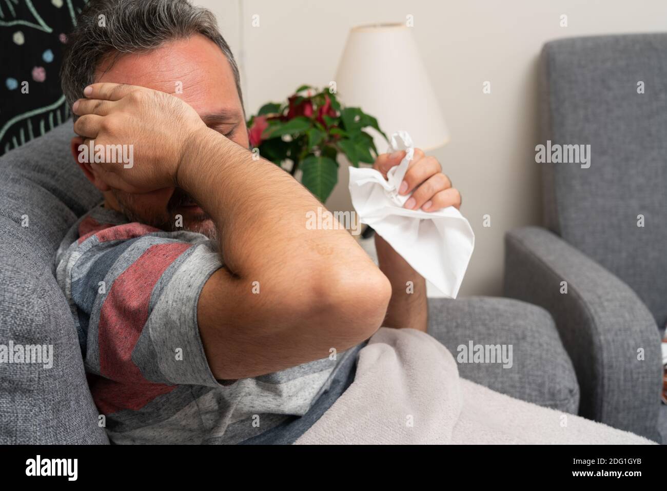 Sick man with sinusitis headache touching forehead holding napkin as cold flu virus infection illness say at home concept feeling unwell Stock Photo