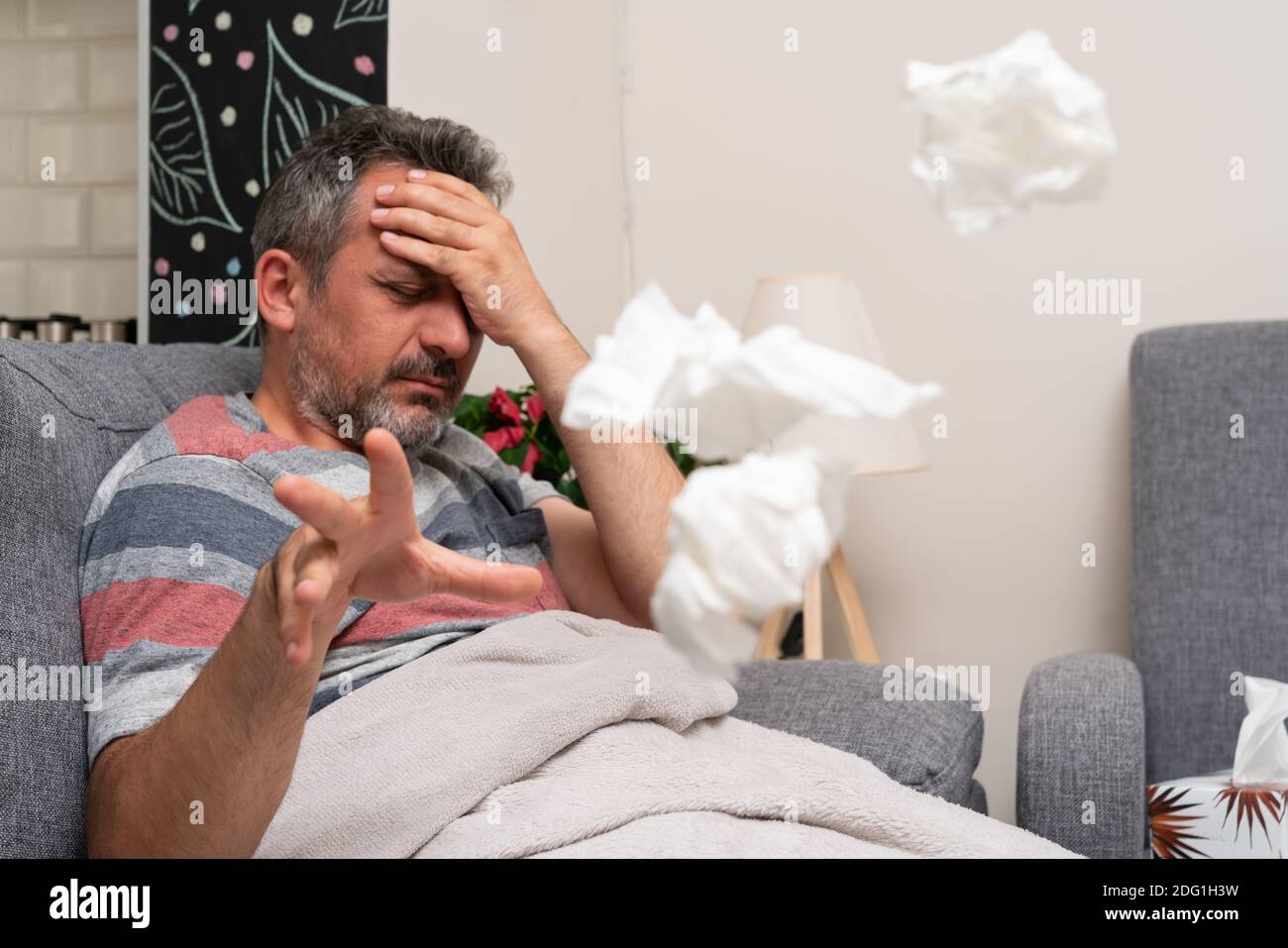 Exhausted adult male model feeling sick unwell touching forehead as migraine or fever concept