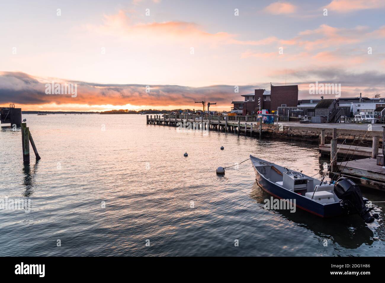 Harbour at sunset. A small moored motorboat with fishing rodsin it is visible in foreground. Stock Photo