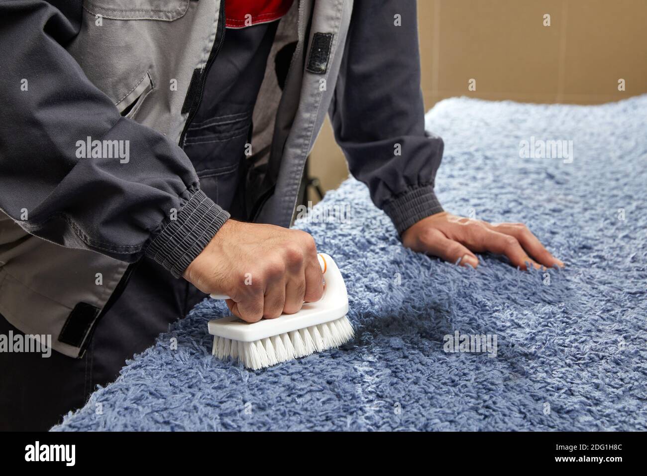 Man Spraying Detergent On Grey Carpet To Remove Stain in professional