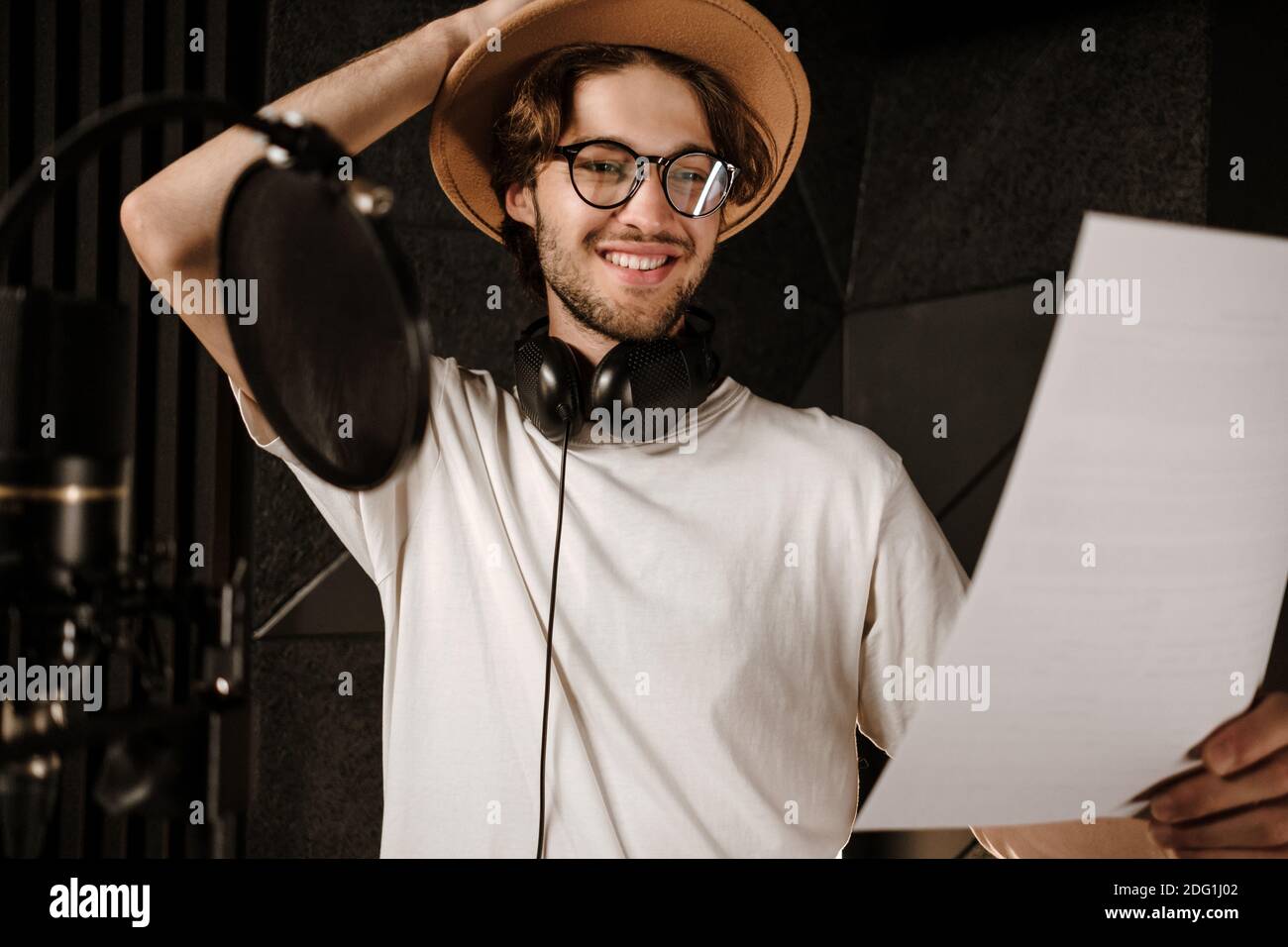 Portrait of young smiling male singer happily reading text of new song ...