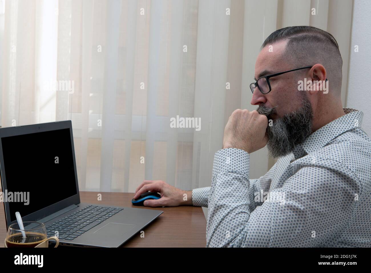 hipster with glasses working remotely with laptop at home using wireless mouse and wi-fi network Stock Photo