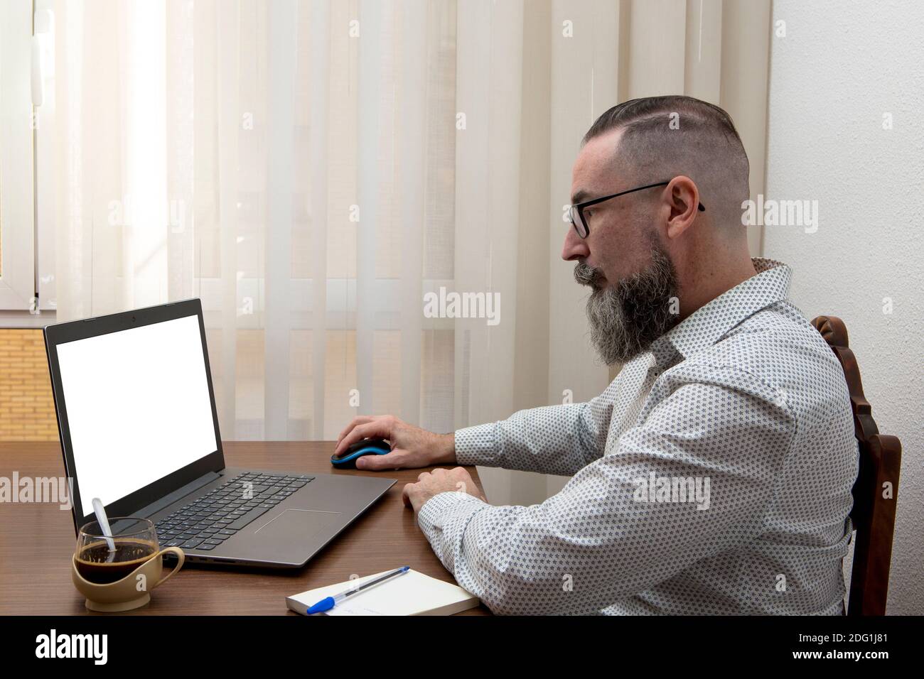 hipster with glasses working remotely with laptop at home using wireless mouse and wi-fi network Stock Photo