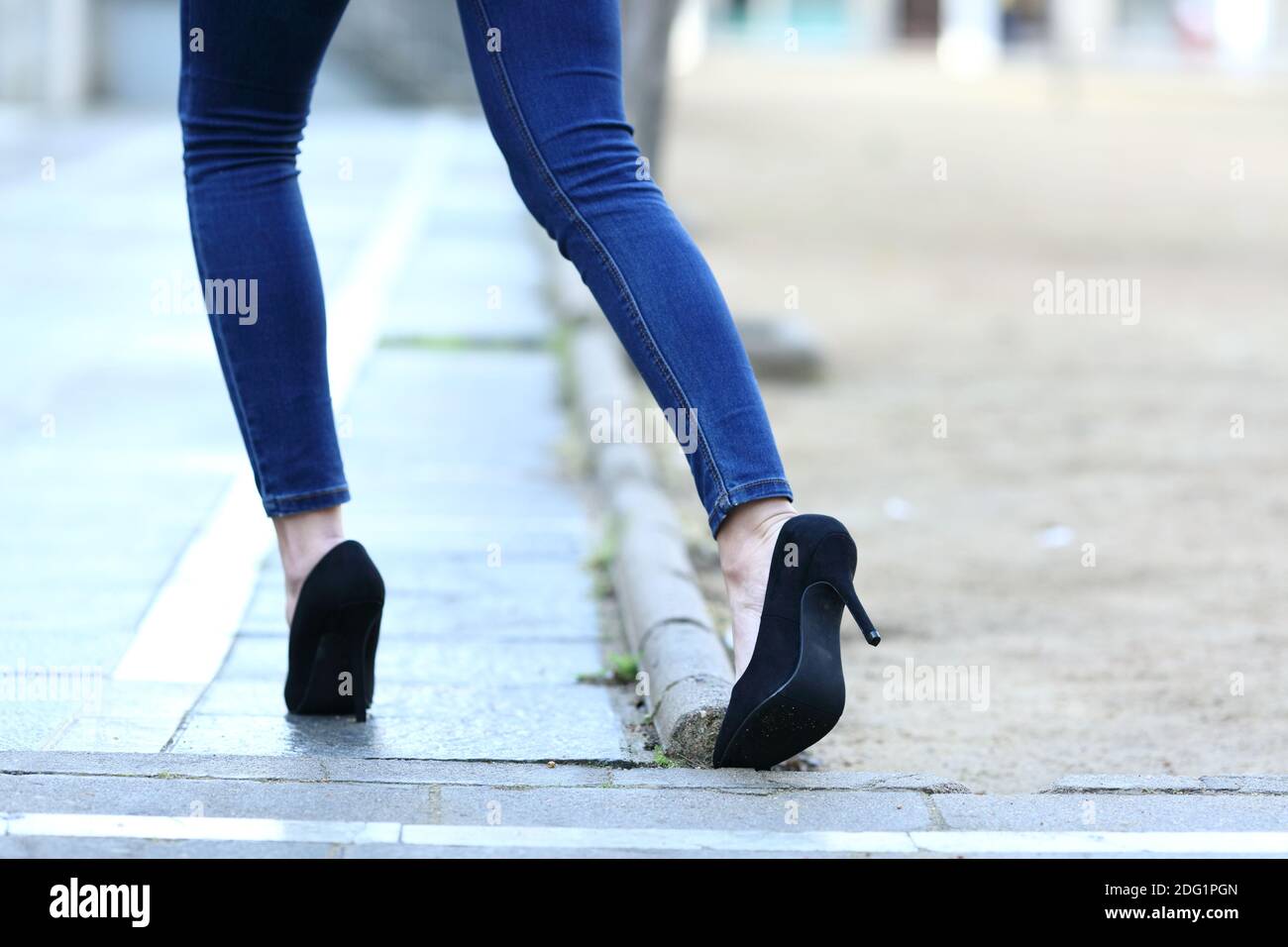 Back view close up of a woman legs with high heels stumbling in the street Stock Photo