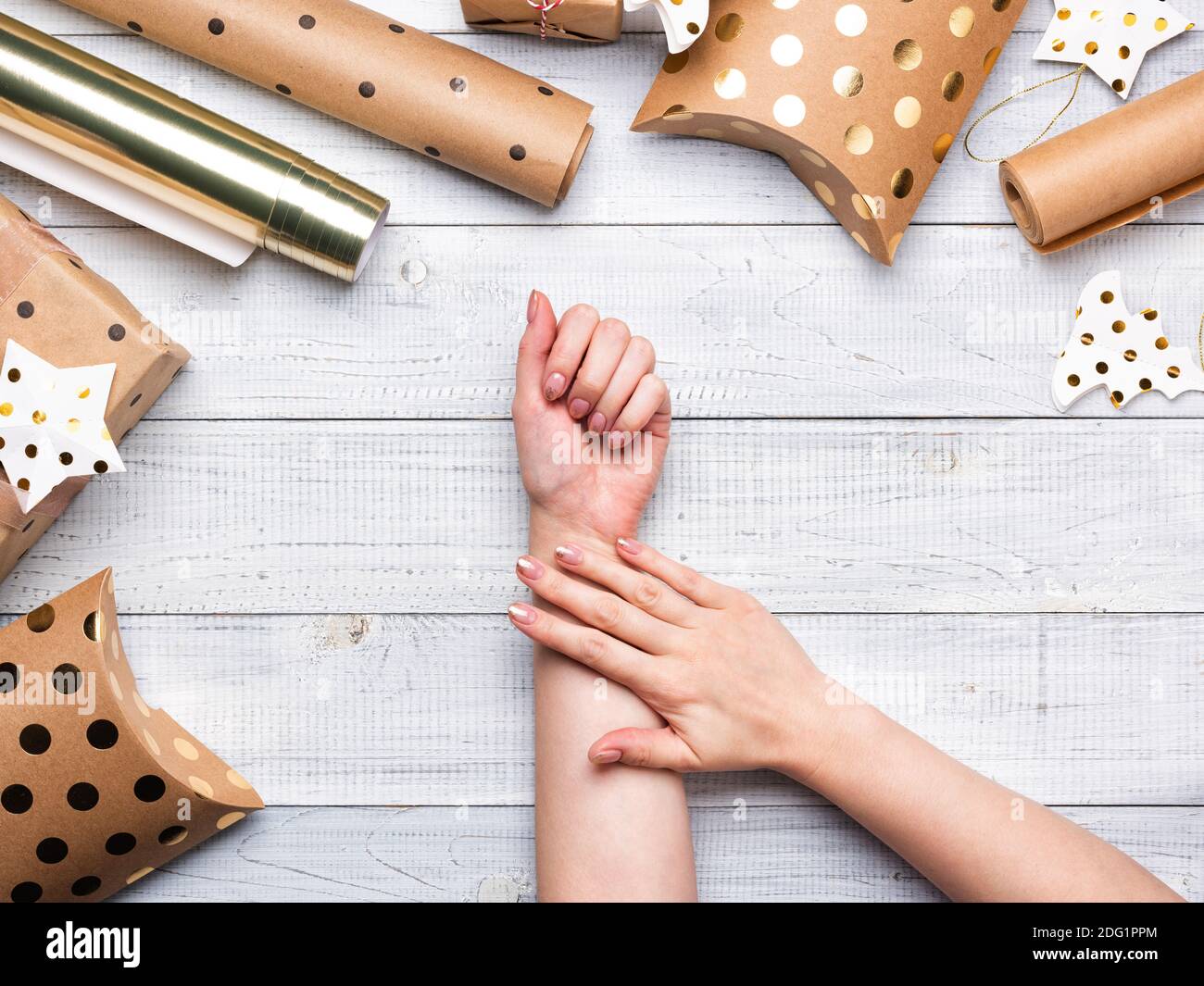 Christmas gift boxes and wrapping paper in gold colors on white wooden background. Copy space for your text. Flat lay and top view. Female hands Stock Photo