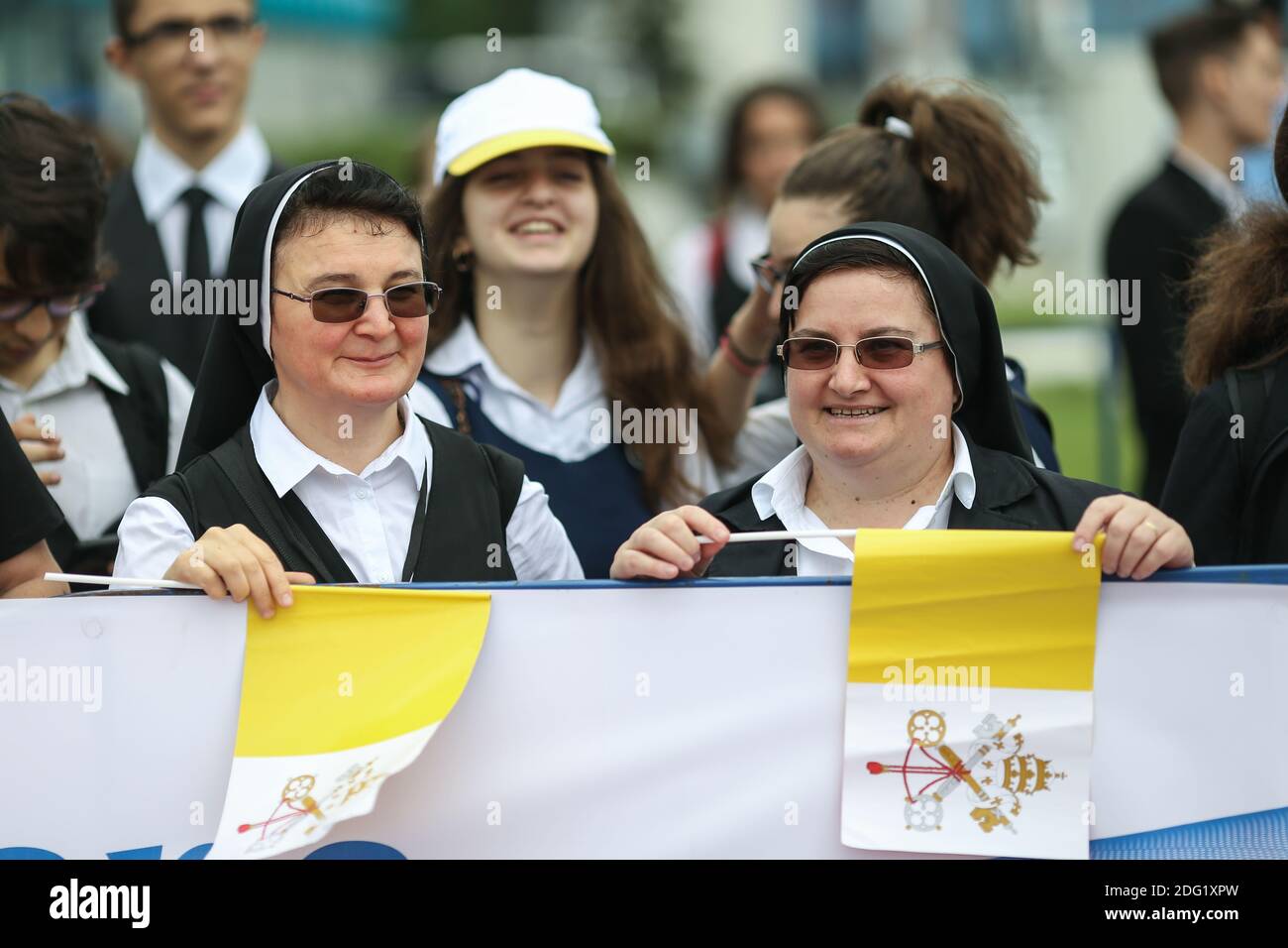 Otopeni, Romania - May 31, 2019: Catholic nuns sing, hold rosaries and Vatican flags while waiting for Pope Francis to come in his first visit in Roma Stock Photo
