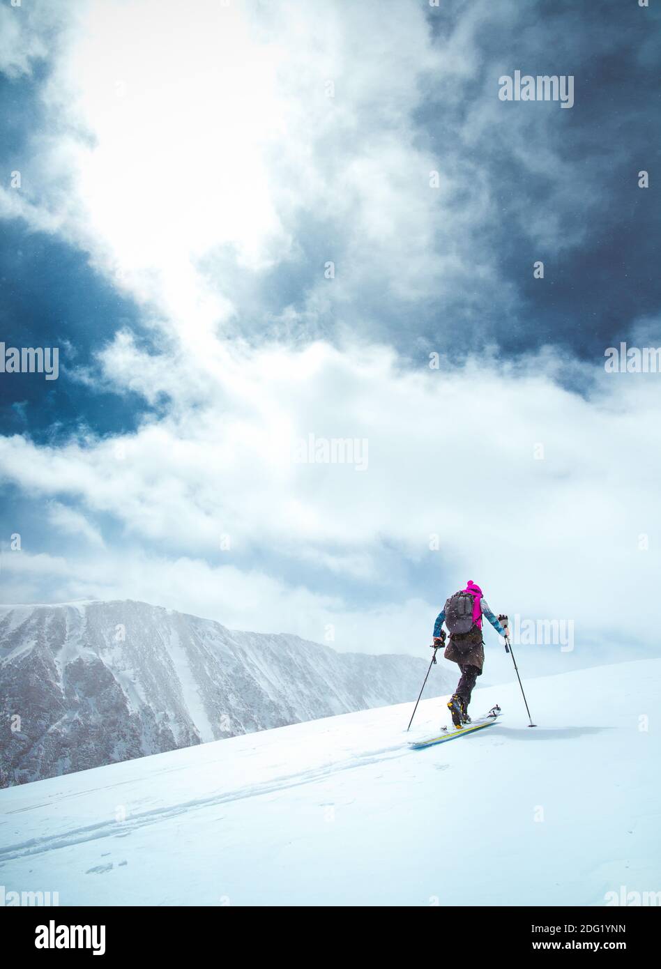 A skier tours up a snowy mountain in Colorado with blue skies Stock Photo