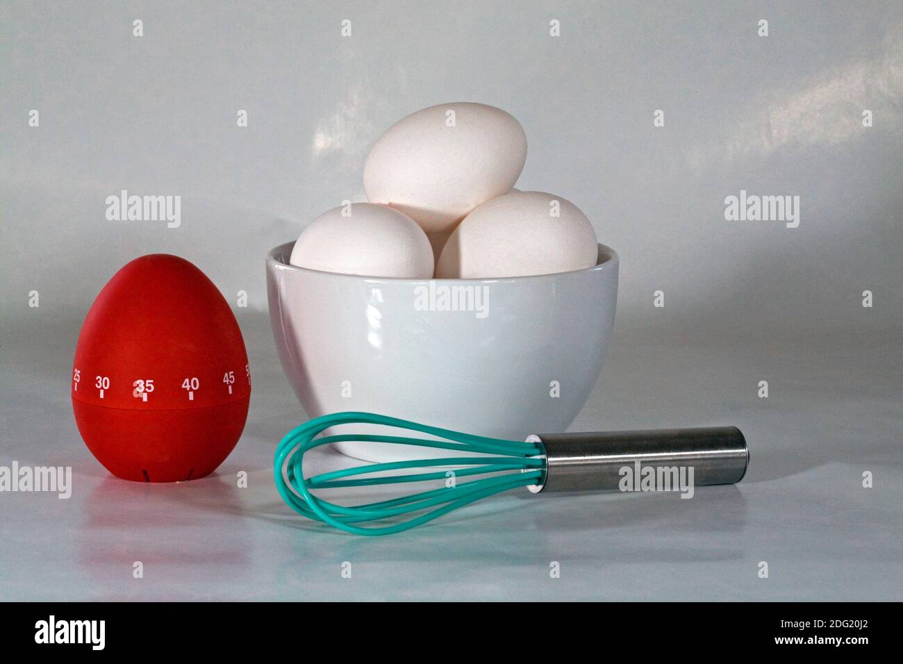 Fresh eggs, a stirring device, and an egg timer, to prepare a healthy breakfast. Stock Photo