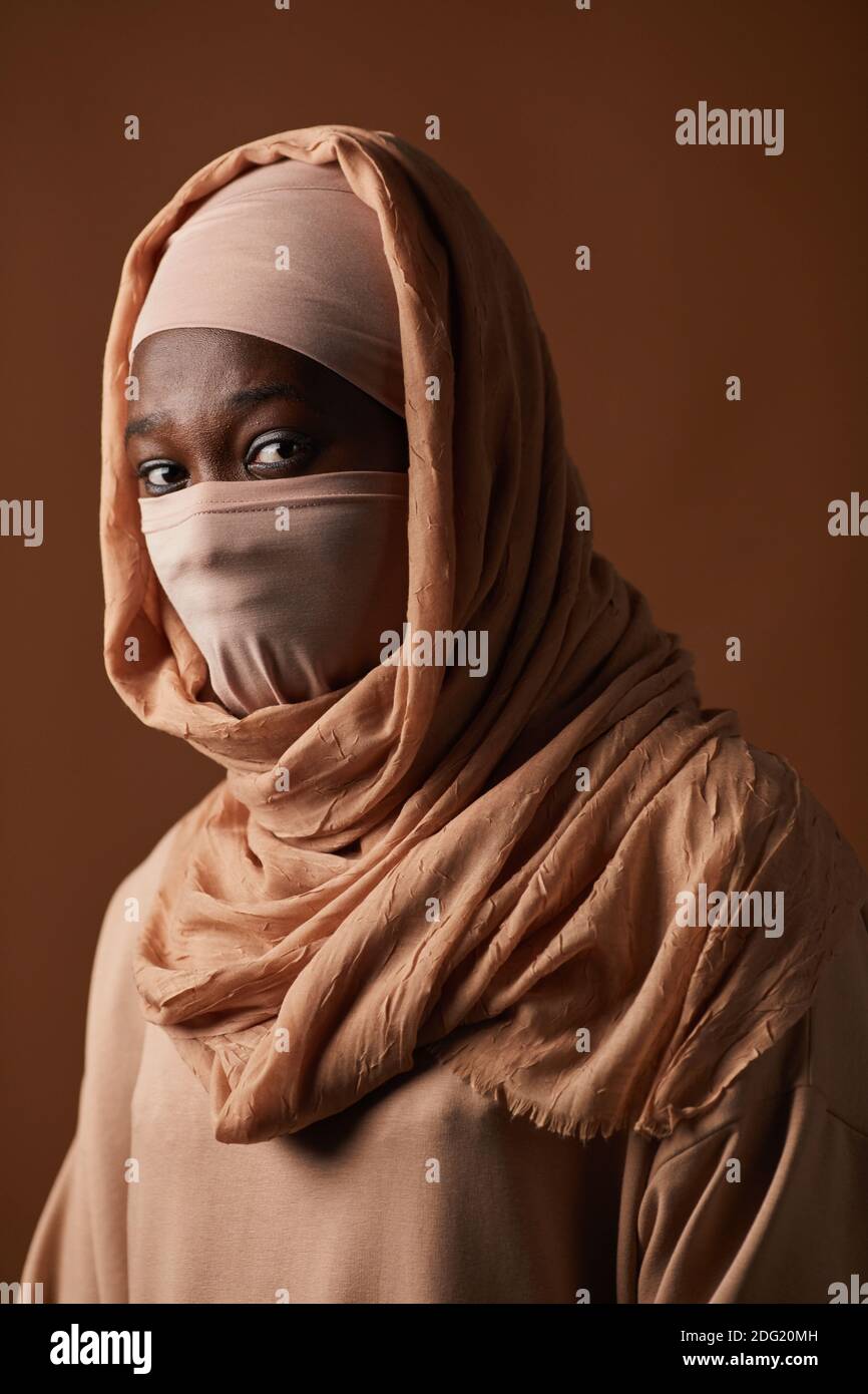 Vertical portrait of ethnic African-American woman wearing face covering and headscarf with focus on eyes, copy space Stock Photo
