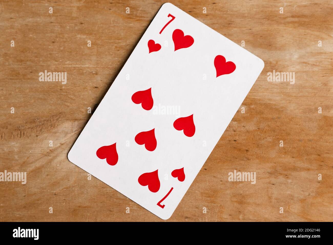 Seven of Hearts playing card, wooden background Stock Photo - Alamy