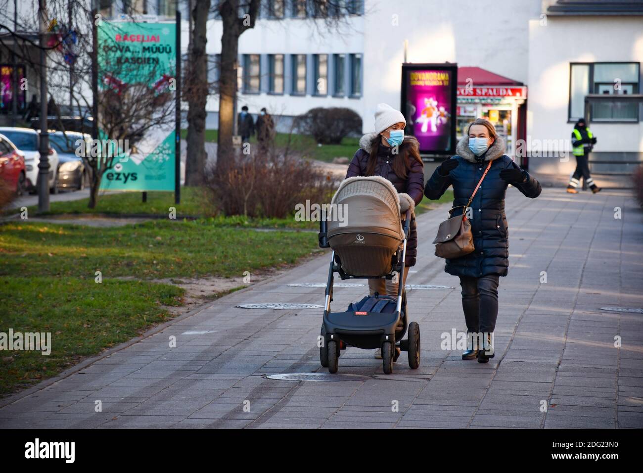 Girl with stroller walking in the city near a shop or shopping center during Covid or Coronavirus outbreak, Christmas background Stock Photo