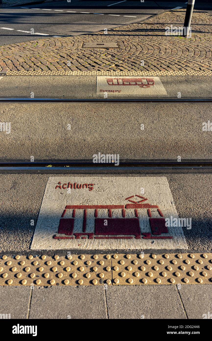 A vertical shot of train signs with an 'Achtung - attention' text on the tram lanes under the sunlight Stock Photo