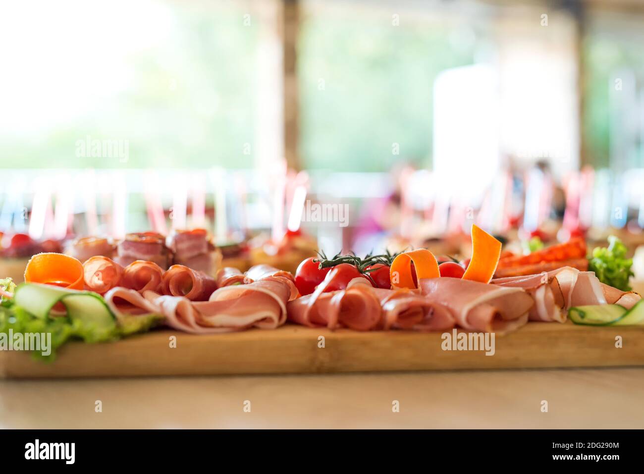 The buffet at the reception. Assortment of canapes on wooden board. Banquet service. Catering, snacks with different types of cheese and meat. Party C Stock Photo