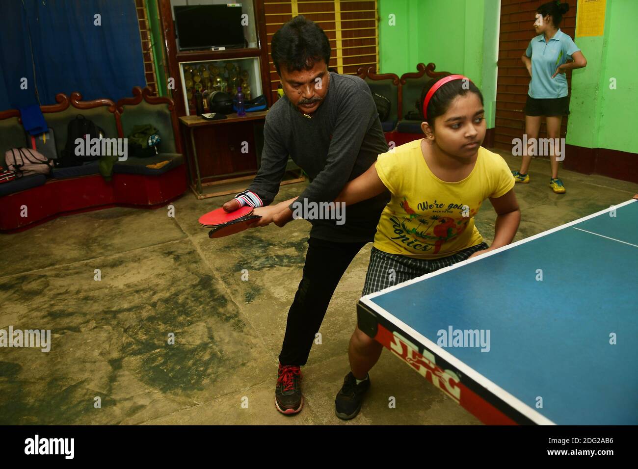 Kajol Dey, a 49 year old disabled table tennis player and coach is seen coaching a young girl at his coaching camp on International Day of Persons with Disabilities (IDPD). Agartala, Tripura, India. Stock Photo