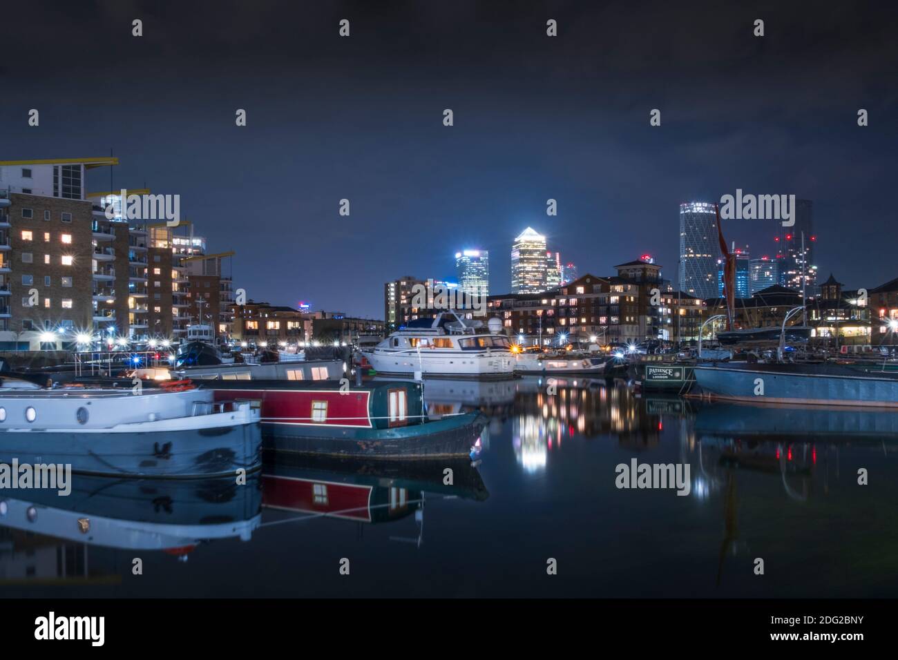 London, Tower Hamlets, Limehouse, Limehouse Basin waterside & marina, houseboats, illuminated skyline of the docklands financial district, night shot Stock Photo