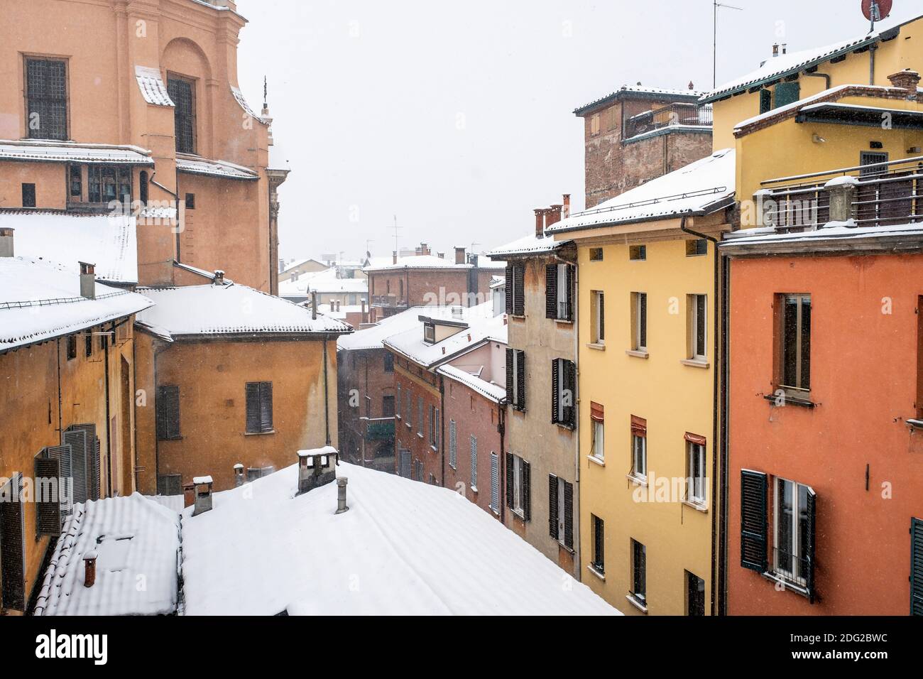 Snow falling on the rooftops of colourful houses in the historic centre of Bologna, Italy Stock