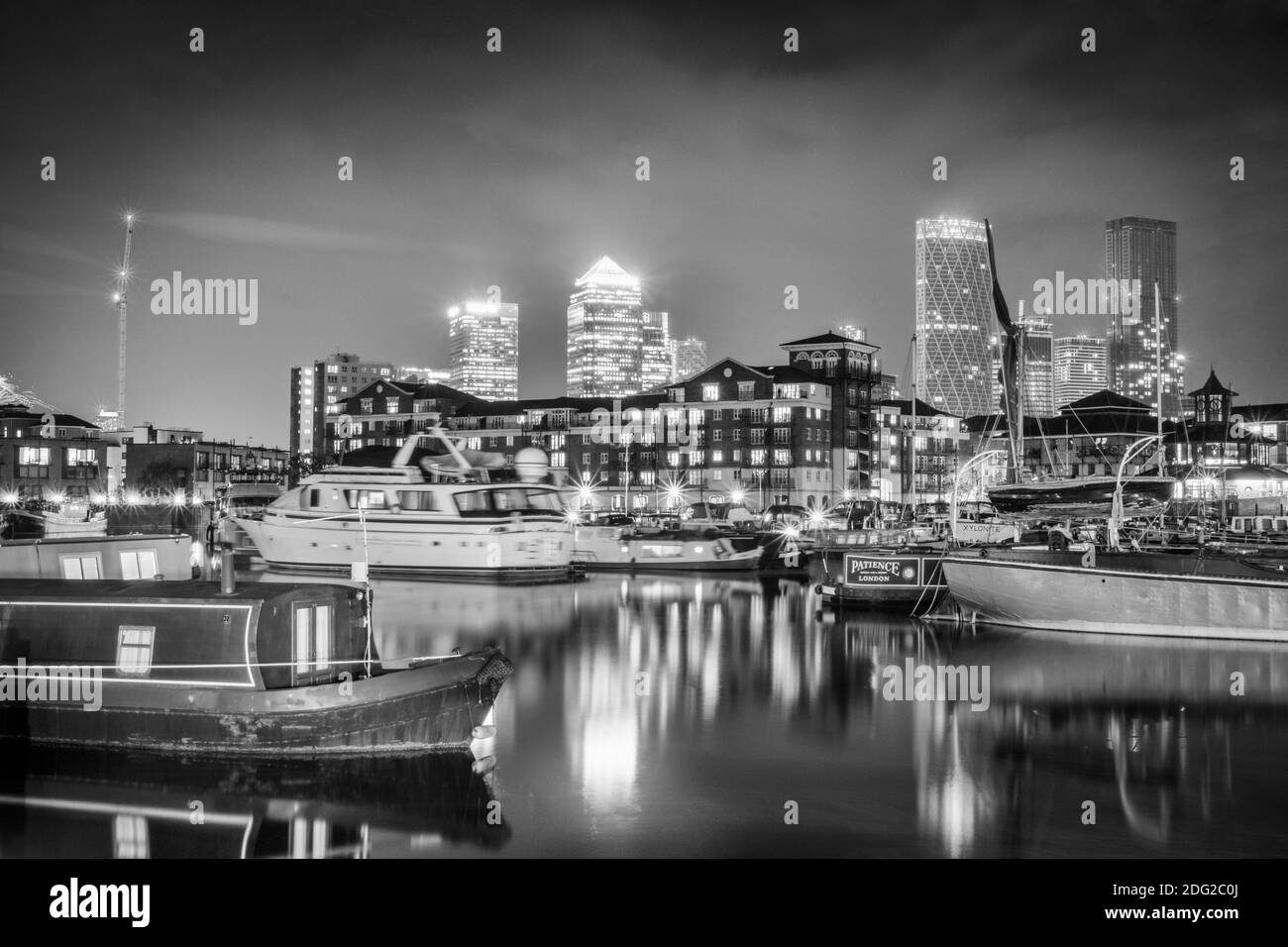 London, Tower Hamlets, Limehouse, Limehouse Basin waterside & marina, houseboats, illuminated skyline of the docklands financial district, night shot Stock Photo