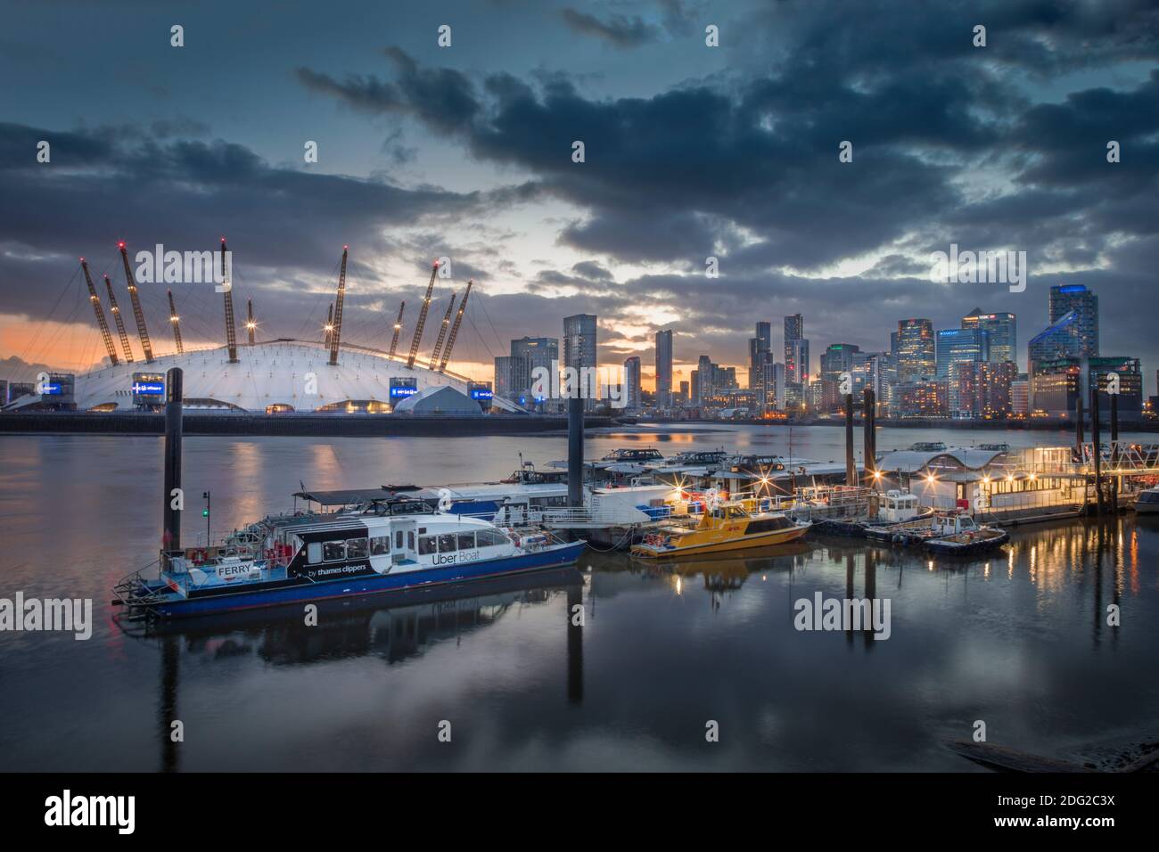 London, skyline of Docklands Canary Wharf commercial centre, O2 concert arena & events venue, river boats on the Thames, dusk, illuminated buildings Stock Photo