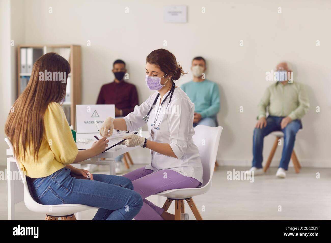 Doctor gives the patient documents to sign before giving her the Covid-19 antiviral vaccine. Stock Photo
