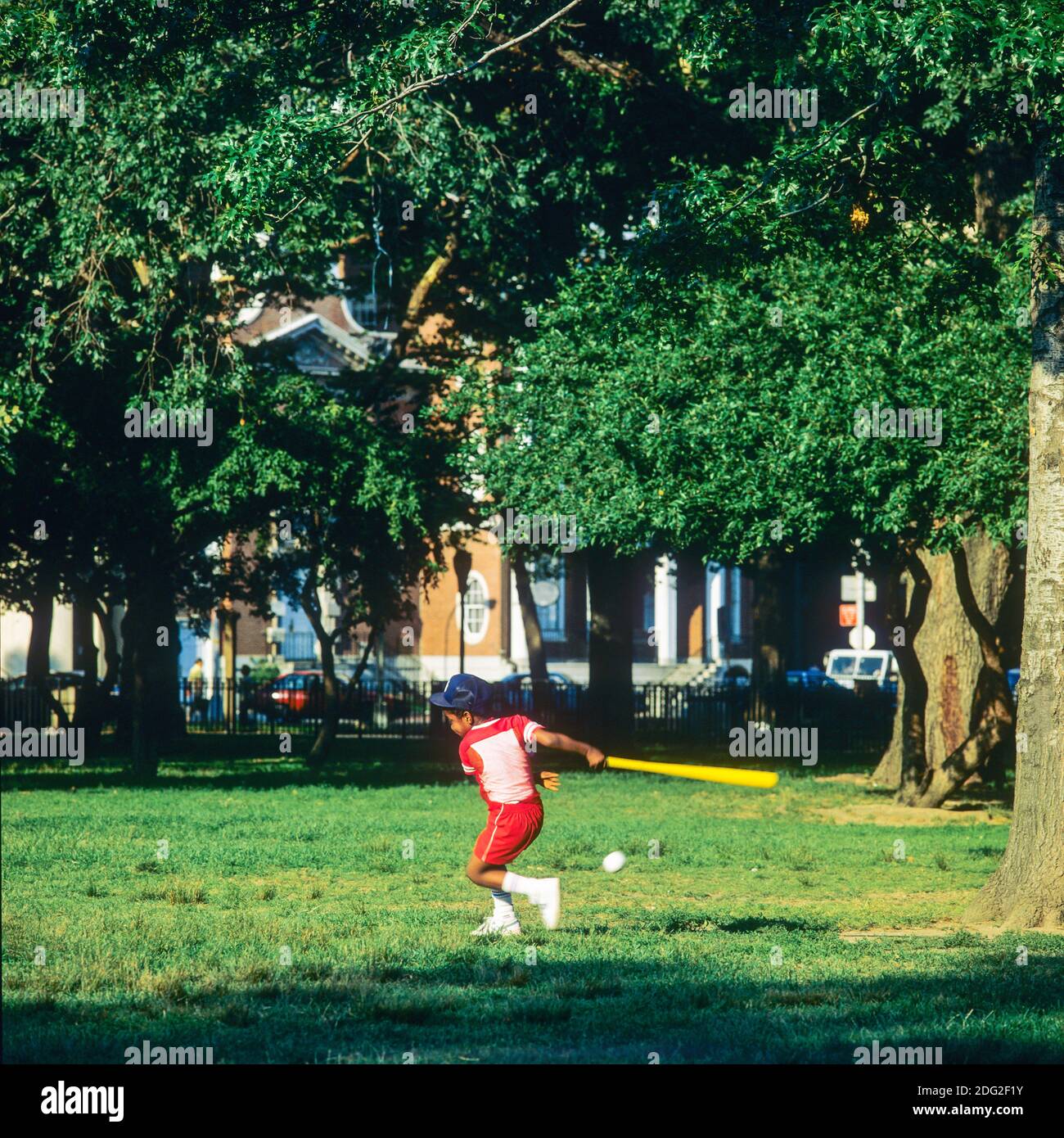 New York 1985, Little African American boy playing baseball, swinging baseball bat, Battery park, lower Manhattan, New York City, NY, NYC, USA, Stock Photo