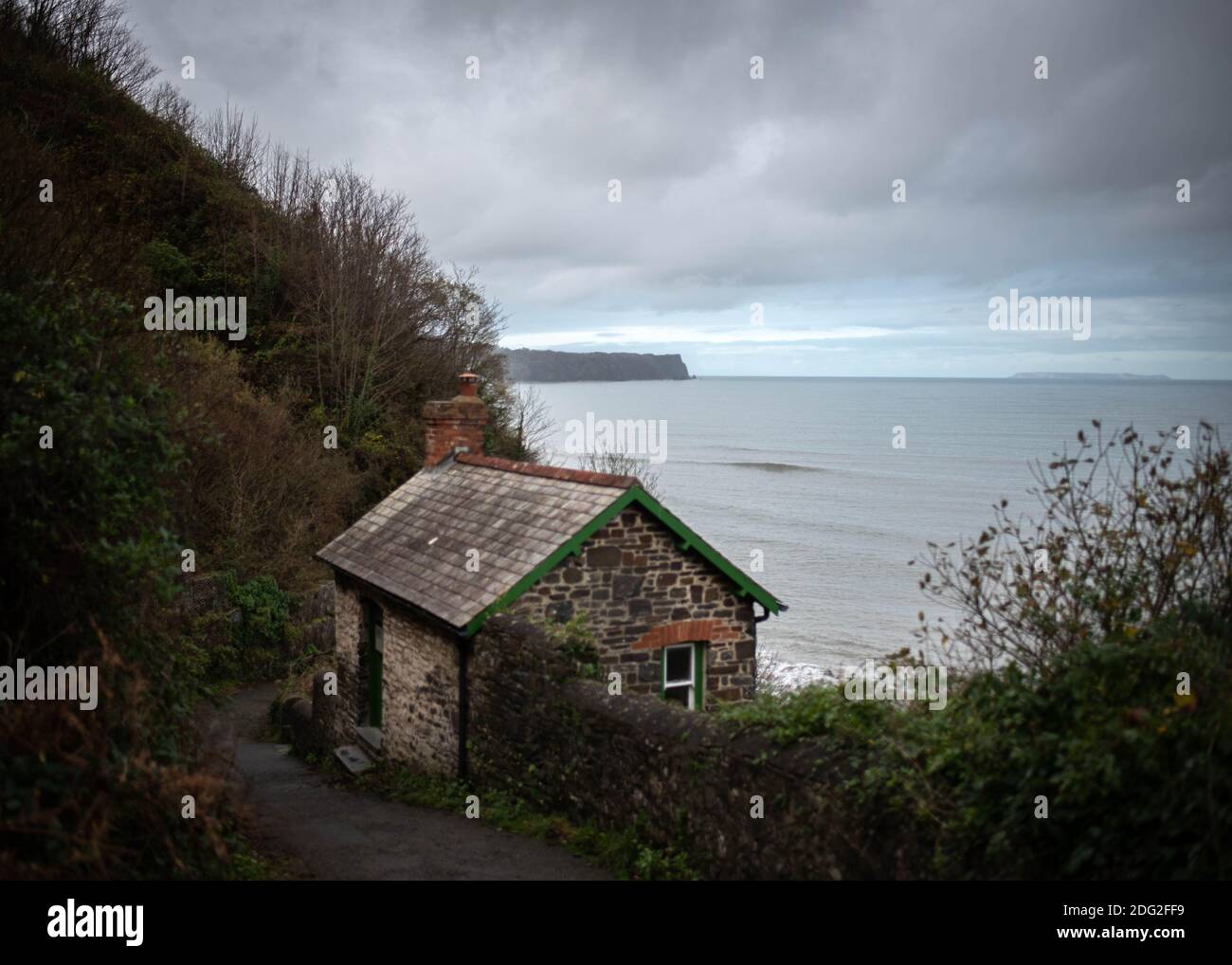 View looking down to the coastline from Bucks Mills village in Devon, England with artist's cabin and Lundy Island visible on horizon. November 2020 Stock Photo