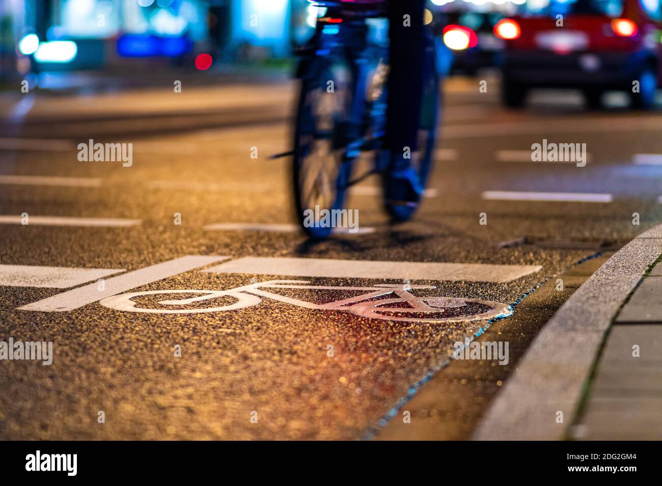 Biker rides ab bike on a street in a big city, passing a bike sign printed on the street Stock Photo