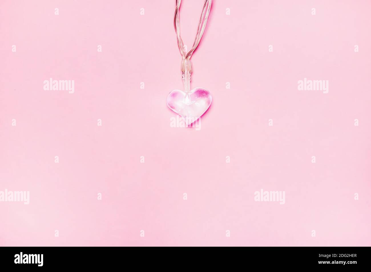 Two small glass hearts on soft pink background. Valentine’s day symbol
