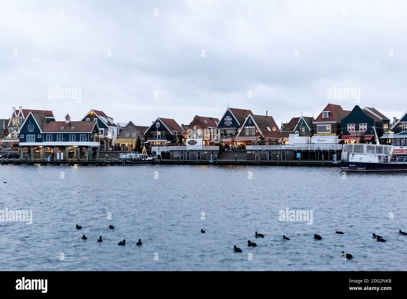 VOLENDAM, NETHERLANDS - December 24, 2019: Dutch harbor with city views, boats, Christmas decorations and ducks. Winter evening in traditional old Stock Photo