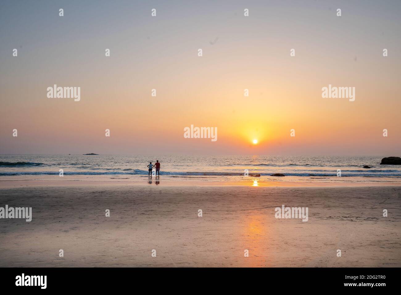 Couple at distance staying and watching amazing sunset at South India (Karnataka or Goa state) Stock Photo