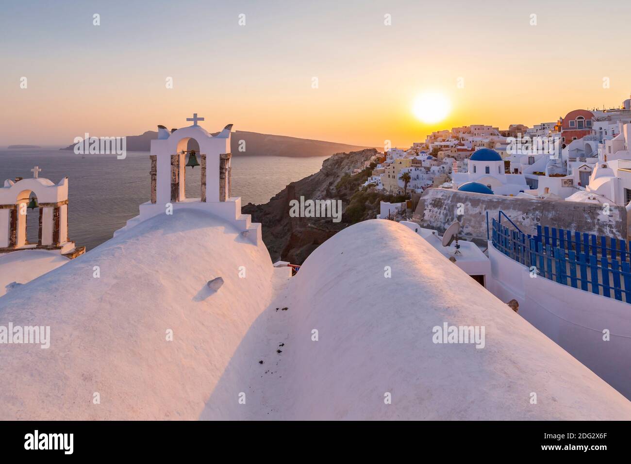View of traditional blue domed churches and white houses at sunset in Oia, Santorini, Greek Islands, Greece, Europe Stock Photo