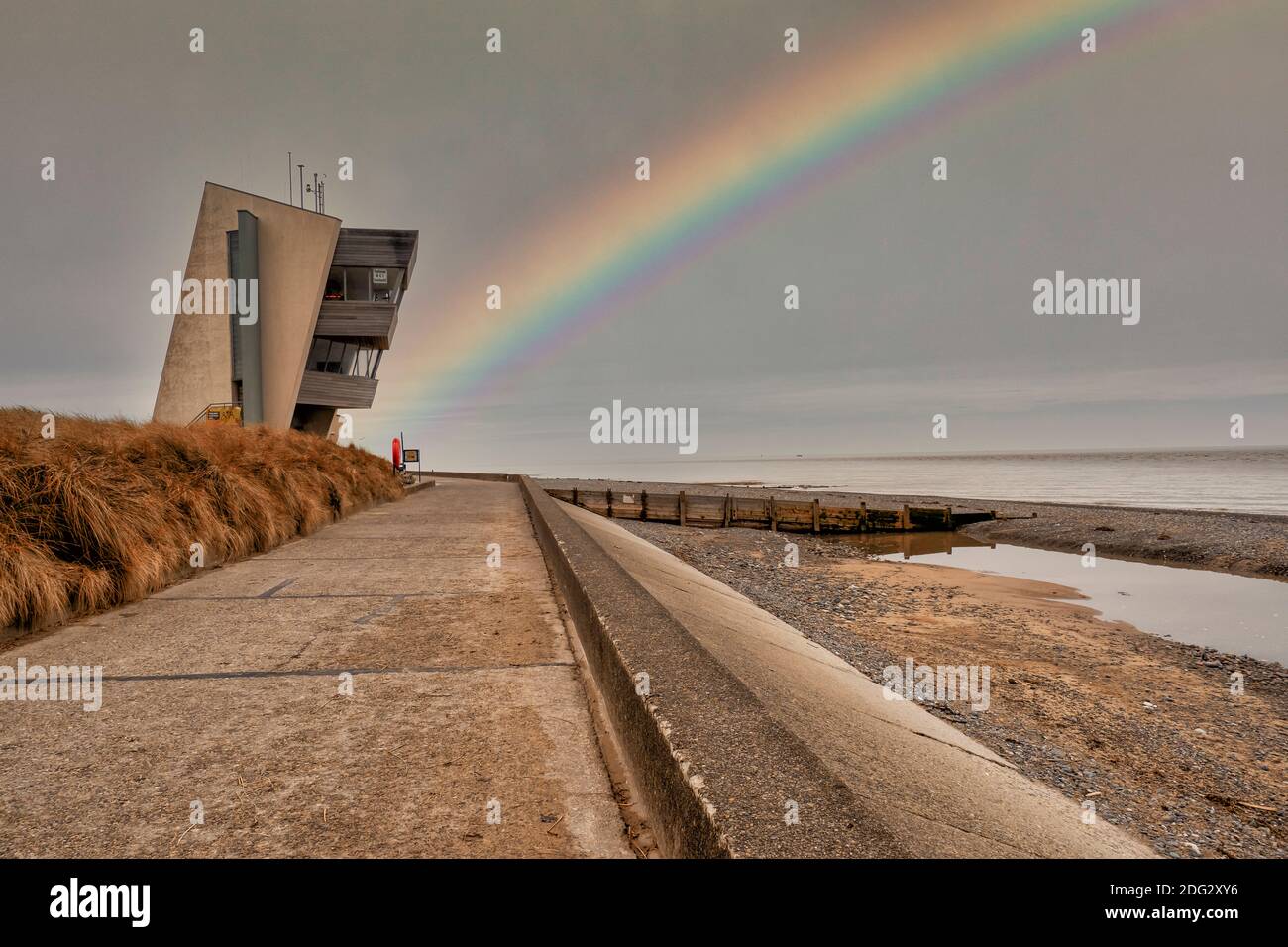 Rainbow at Rossall Beach, Fleetwood, Lancashire, UK. The four storey building on the outer promenade at Rossall Point is Rossall Coastwatch Tower. Stock Photo