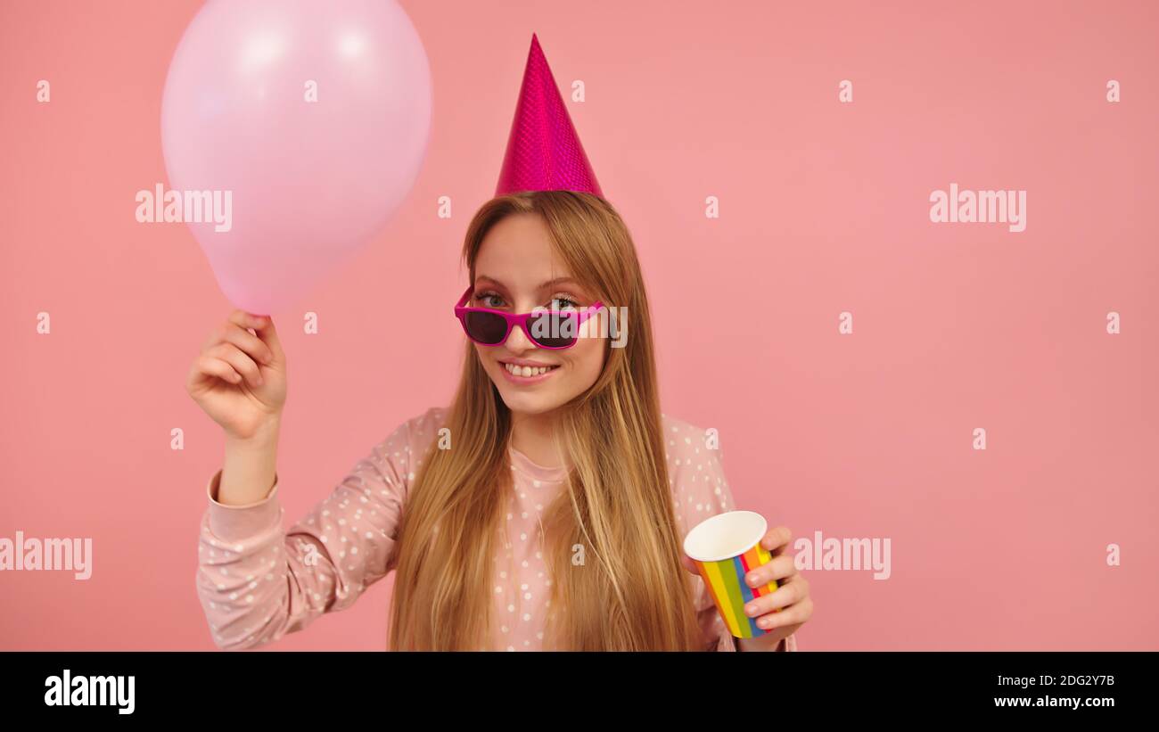 Happy woman with party hat ballon and cup in her hands isolated on pink background. High quality photo Stock Photo - Alamy