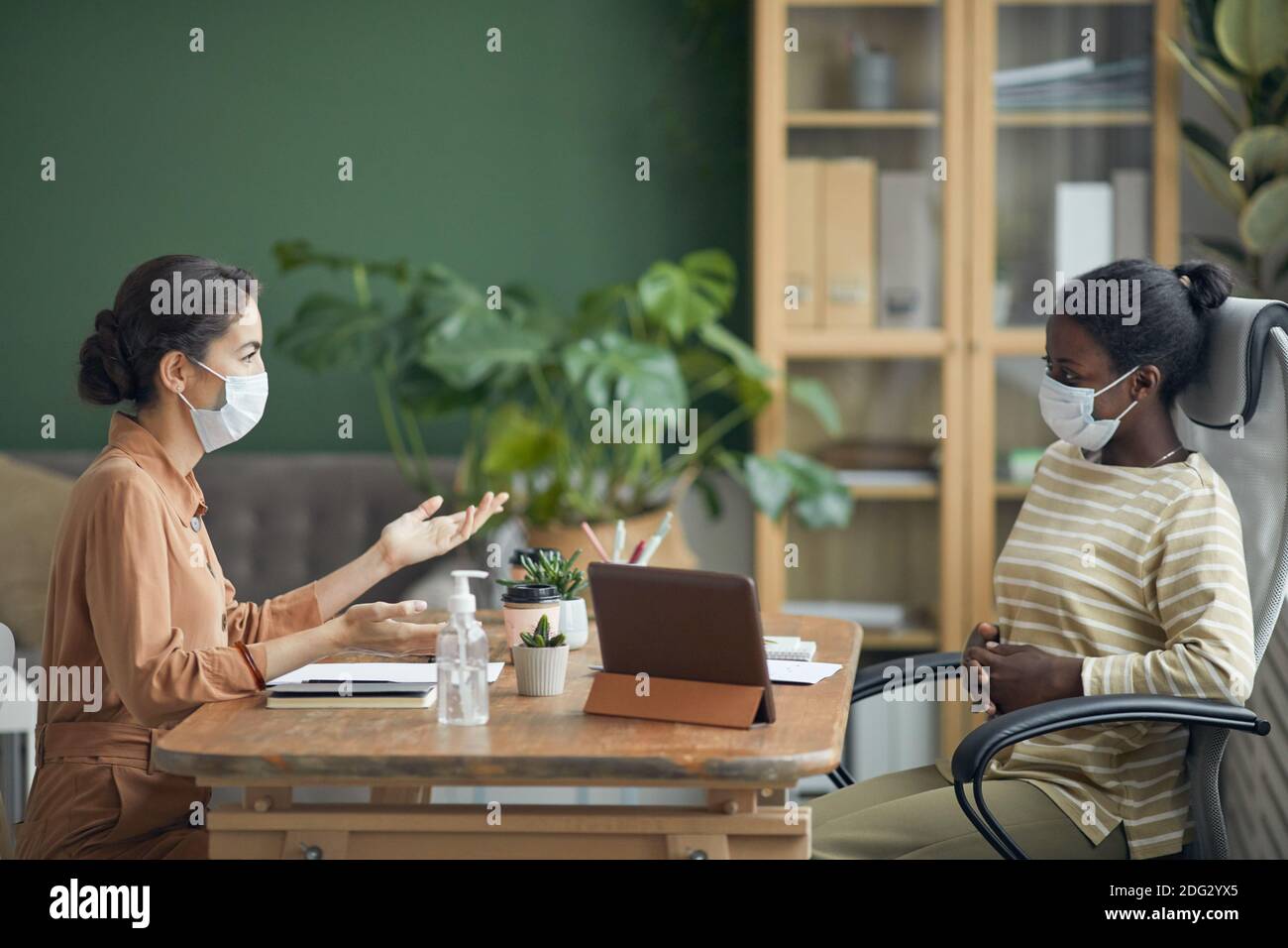 Side view portrait of two businesswomen wearing masks during job
