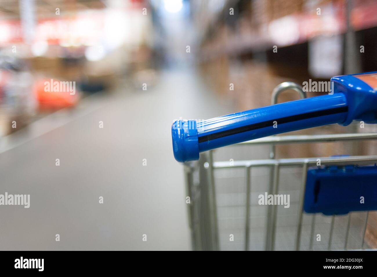 Closeup of shopping cart part with the perspective view of shopping mall shelves with goods Stock Photo