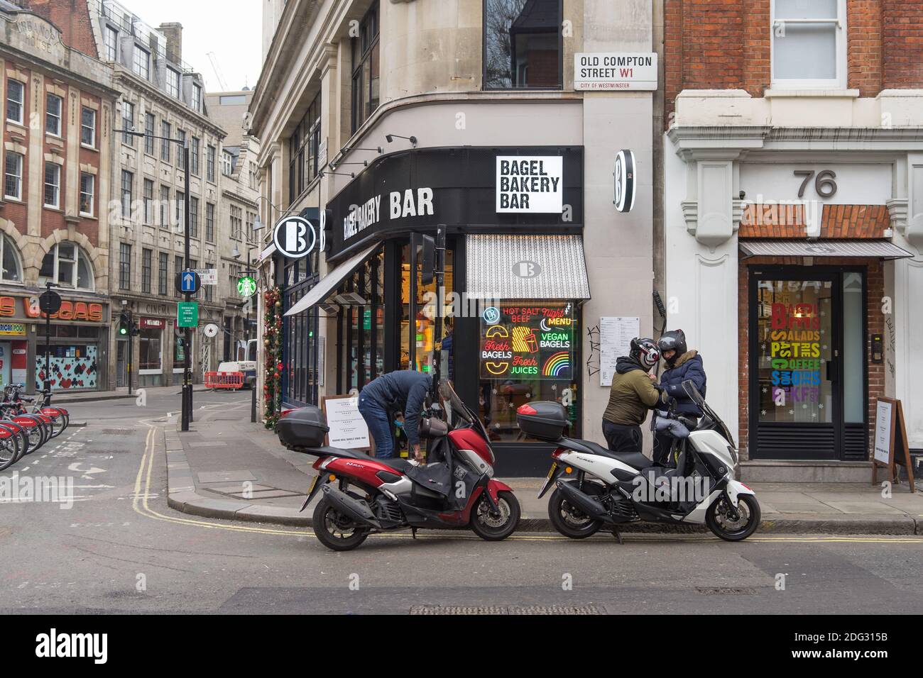 Moped delivery drivers wait outside a bakery on Old Compton Street, Soho. London Stock Photo