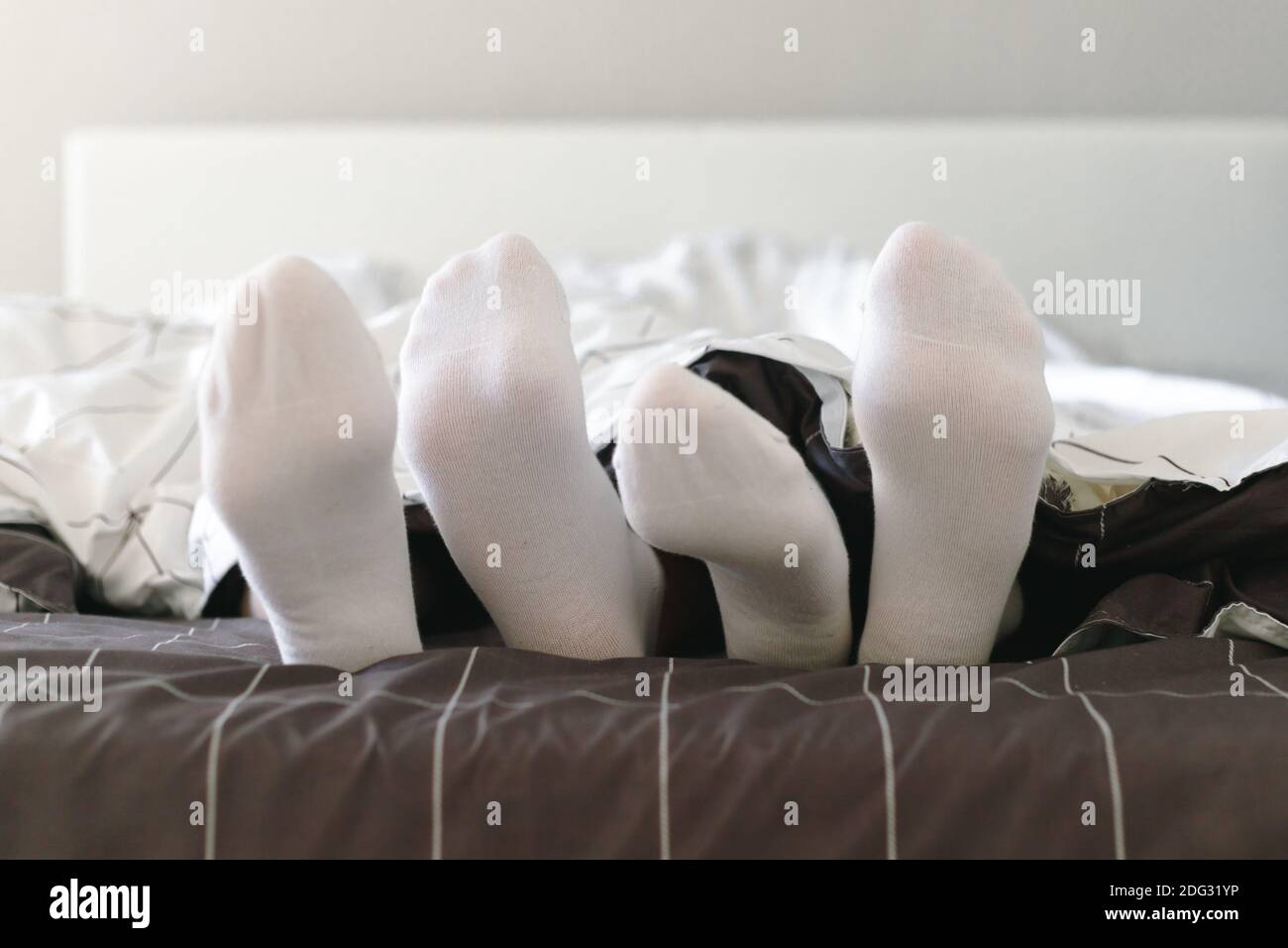 Couple in white socks lying in bed. Lovers together in the morning. Stock Photo