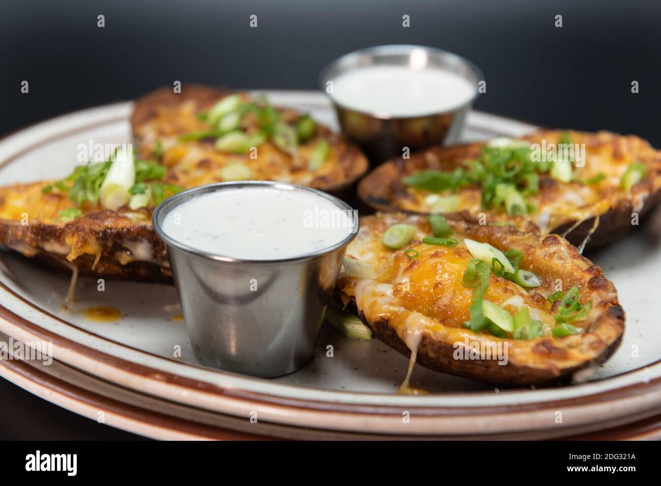 Side dish appetizer of steak stuffed potato skins served on a plate with sour cream dipping sauce. Stock Photo