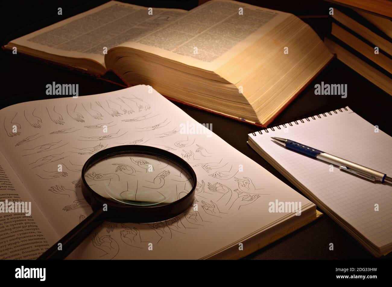 Open book and magnifier located on a dark table and a dark background Stock Photo