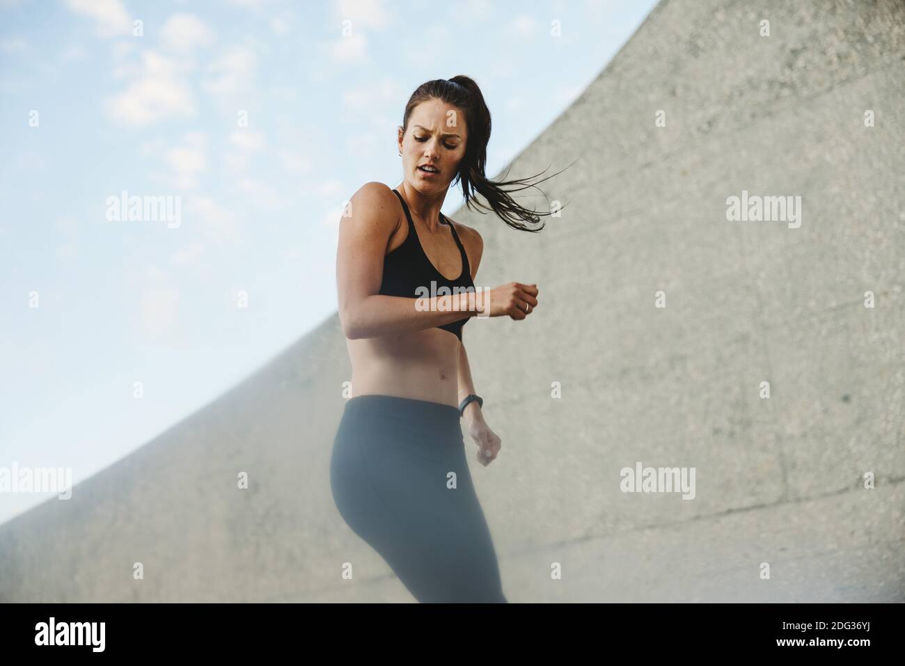 Woman exercising outdoors in morning. Female in black sports clothing doing fitness training. Stock Photo
